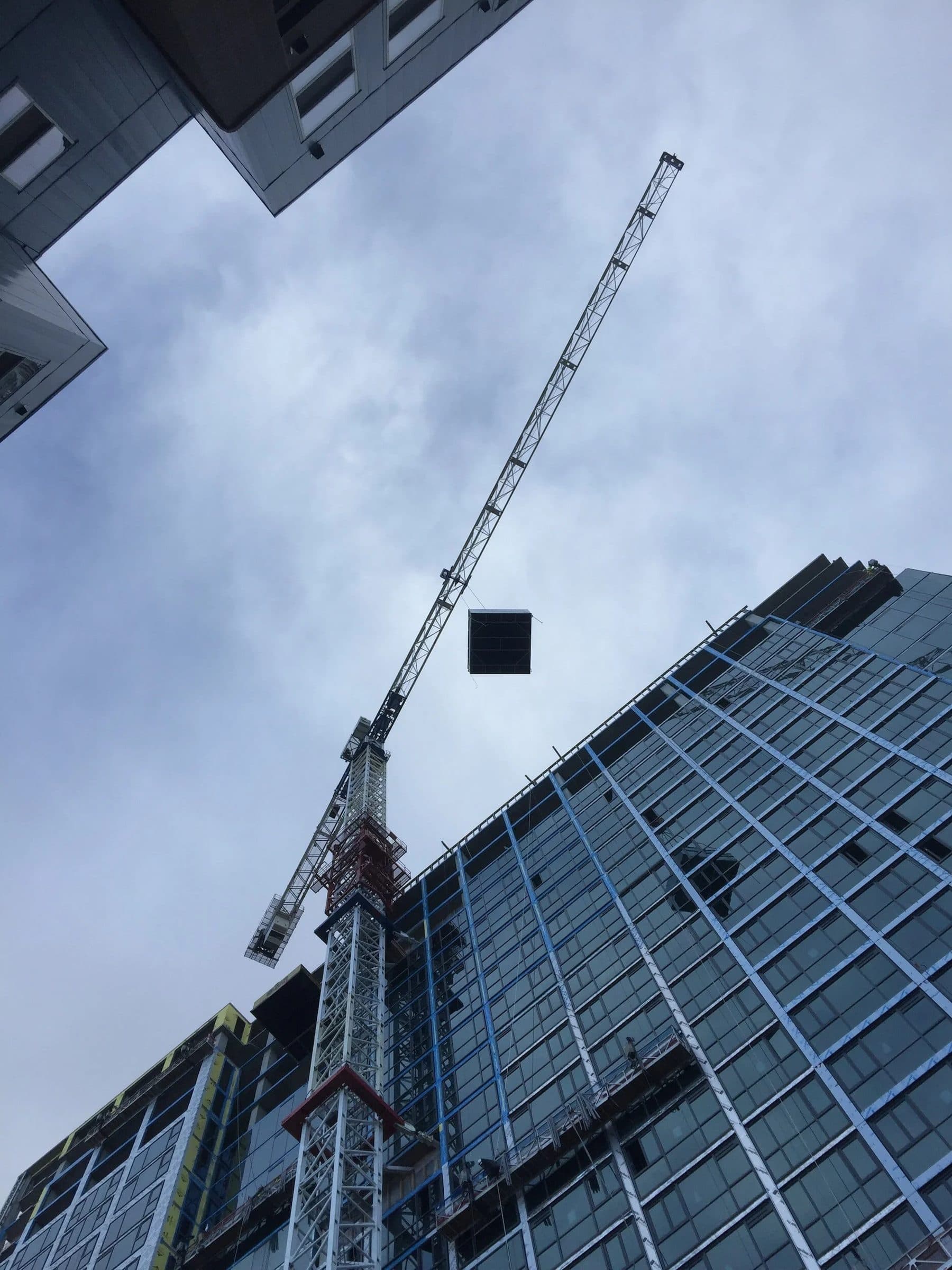 Looking up a tower crane beside a glass high-rise under construction